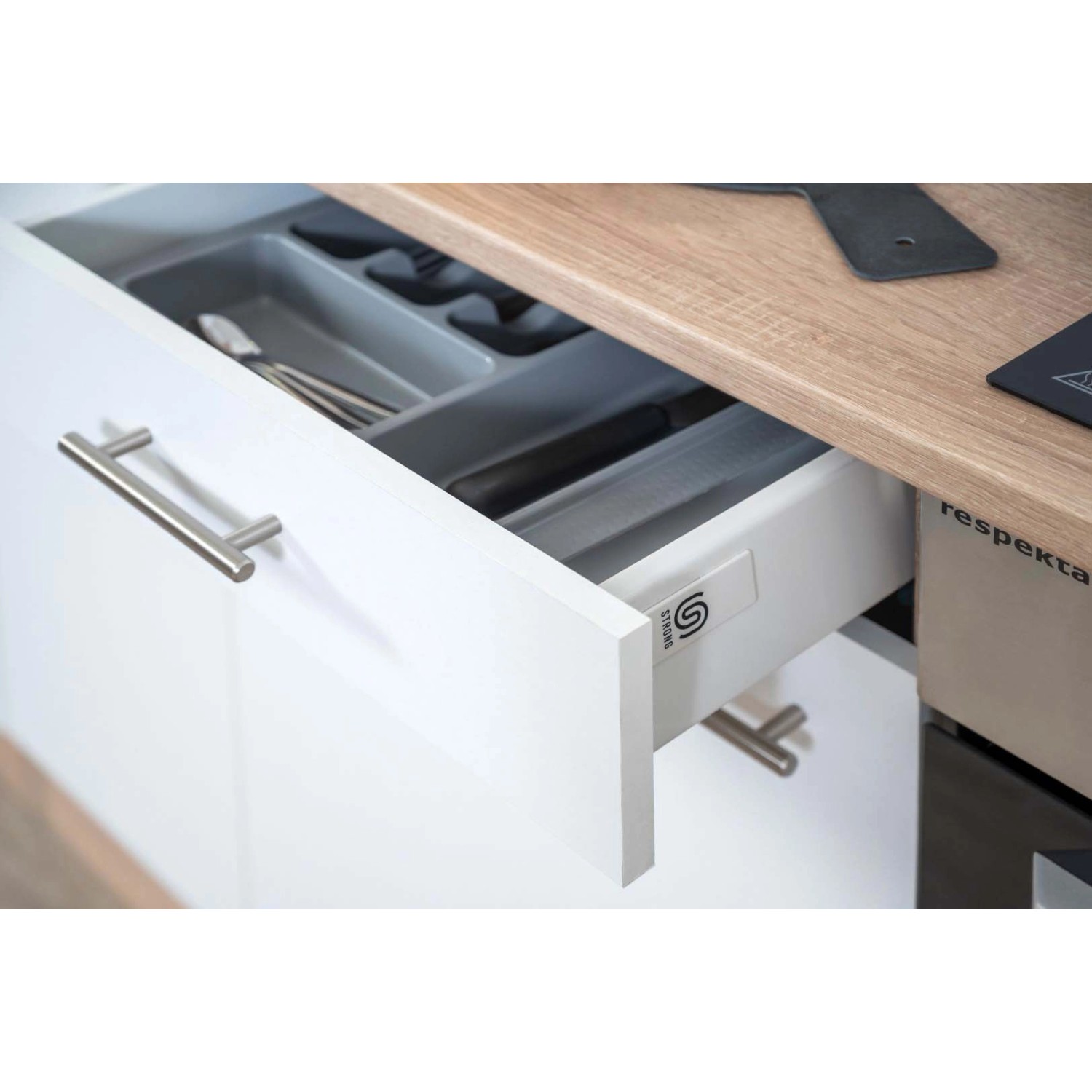 Detailaufnahme: Geöffnete Schublade der Respekta Küchenzeile in Weiß-Eiche Sägerau mit Besteckeinsatz.