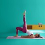 Frau macht Yoga mit WiZ LED Stehleuchte im Hintergrund, die farbiges Licht an die Wand wirft.