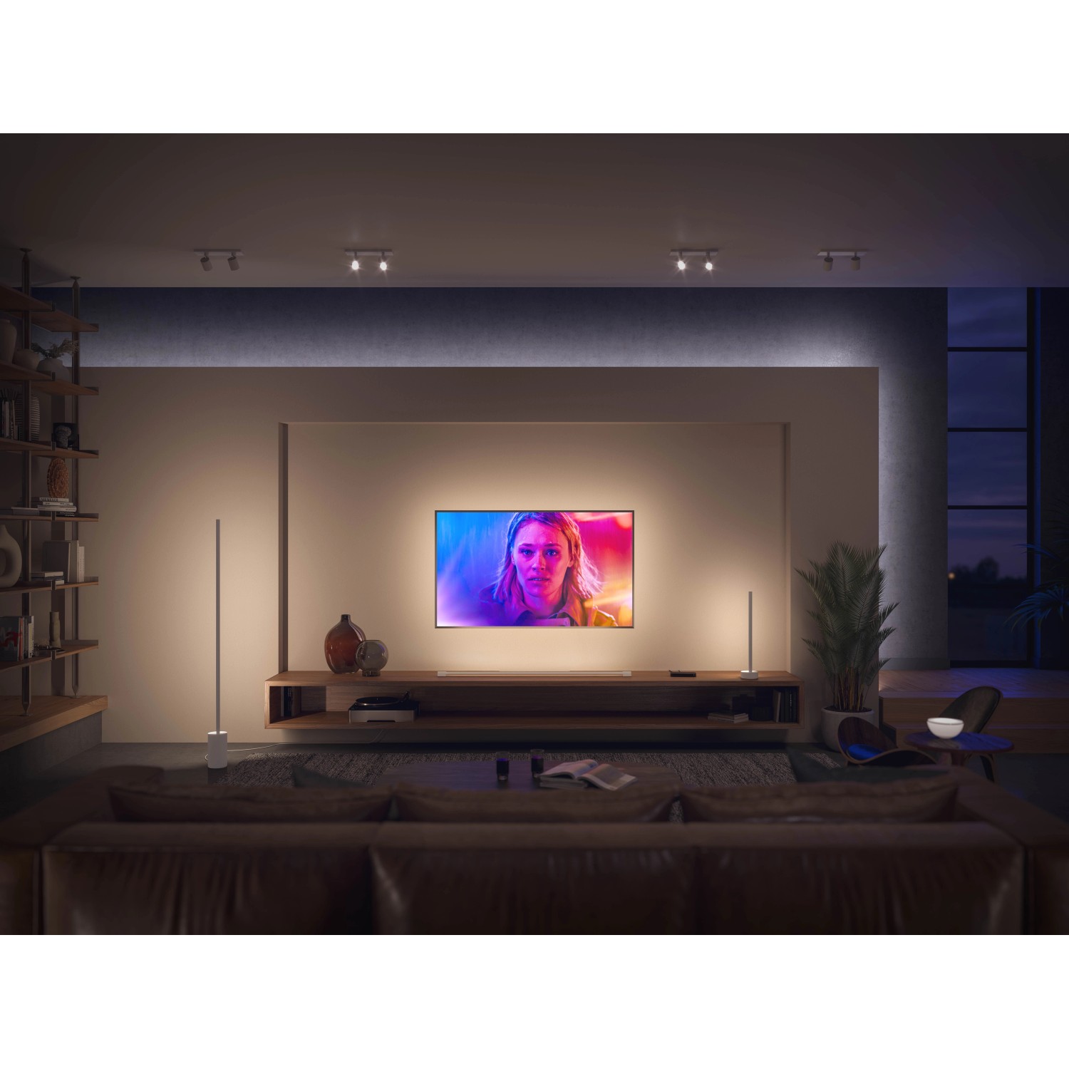 Weiße Philips Hue Gradient Signe Tischleuchte im Wohnzimmer mit TV und Sofa.