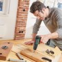 Mann bohrt mit Bosch Akkuschrauber UniversalImpact 18 in Holz. Inkl. Akku und Koffer.