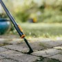 Fiskars OneClick Fugenkratzer in Aktion: Unkrautentfernung zwischen Pflastersteinen.