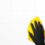 Hand mit schwarzem Einmalhandschuh reinigt weiße Fliesen mit gelbem Tuch. Latexfrei, Größe S.