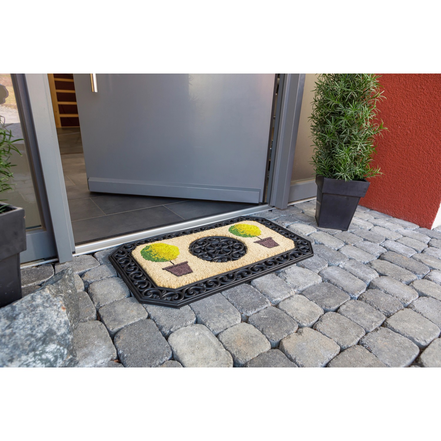 Fußmatte Coco Twin mit Bäume-Motiv, 45x75 cm, achteckig, vor einer Haustür.