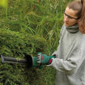 Frau schneidet Hecke mit Bosch Akku-Heckenschere EasyHedgeCut 18V. Heckenschnitt mit Akku-Gerät.