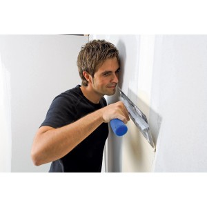 Mann trägt Knauf Uniglett Innenspachtel auf Wand auf. Spezialspachtel für glatte Oberflächen.