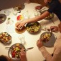 Esstisch mit Personen, Tellern, Salatschüssel, Kartoffeln und Getränken.