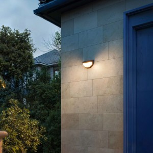Schwarze Philips Solar-Wandleuchte Swyn an Hauswand mit warmweißem Licht.