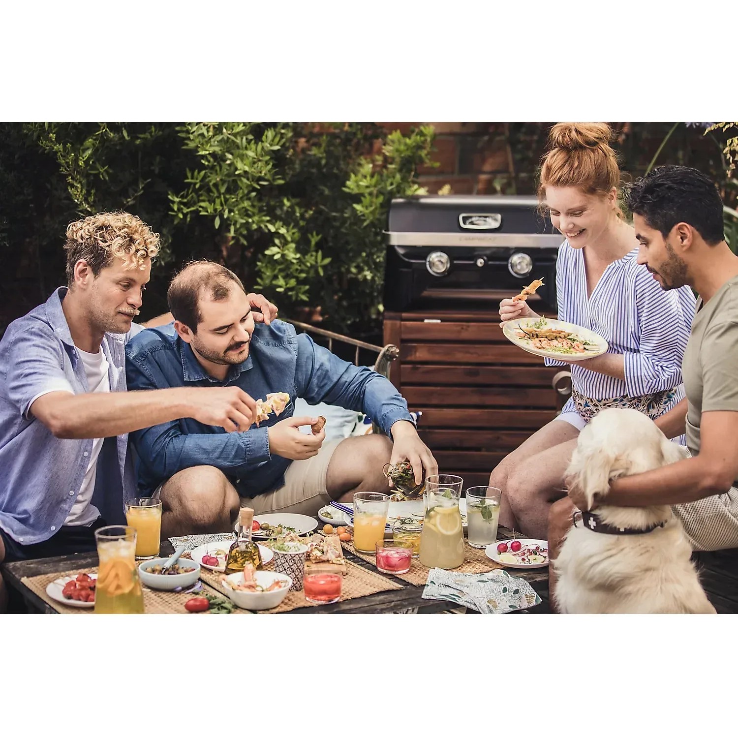 Gruppe genießt Grillabend mit Campingaz Gas-Tischgrill Attitude 2100 LX im Garten.