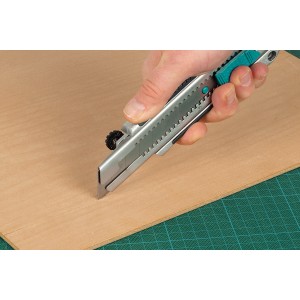 Wolfcraft Profi-Abbrechklingenmesser 25 mm schneidet Holzplatte auf grüner Schneidematte.