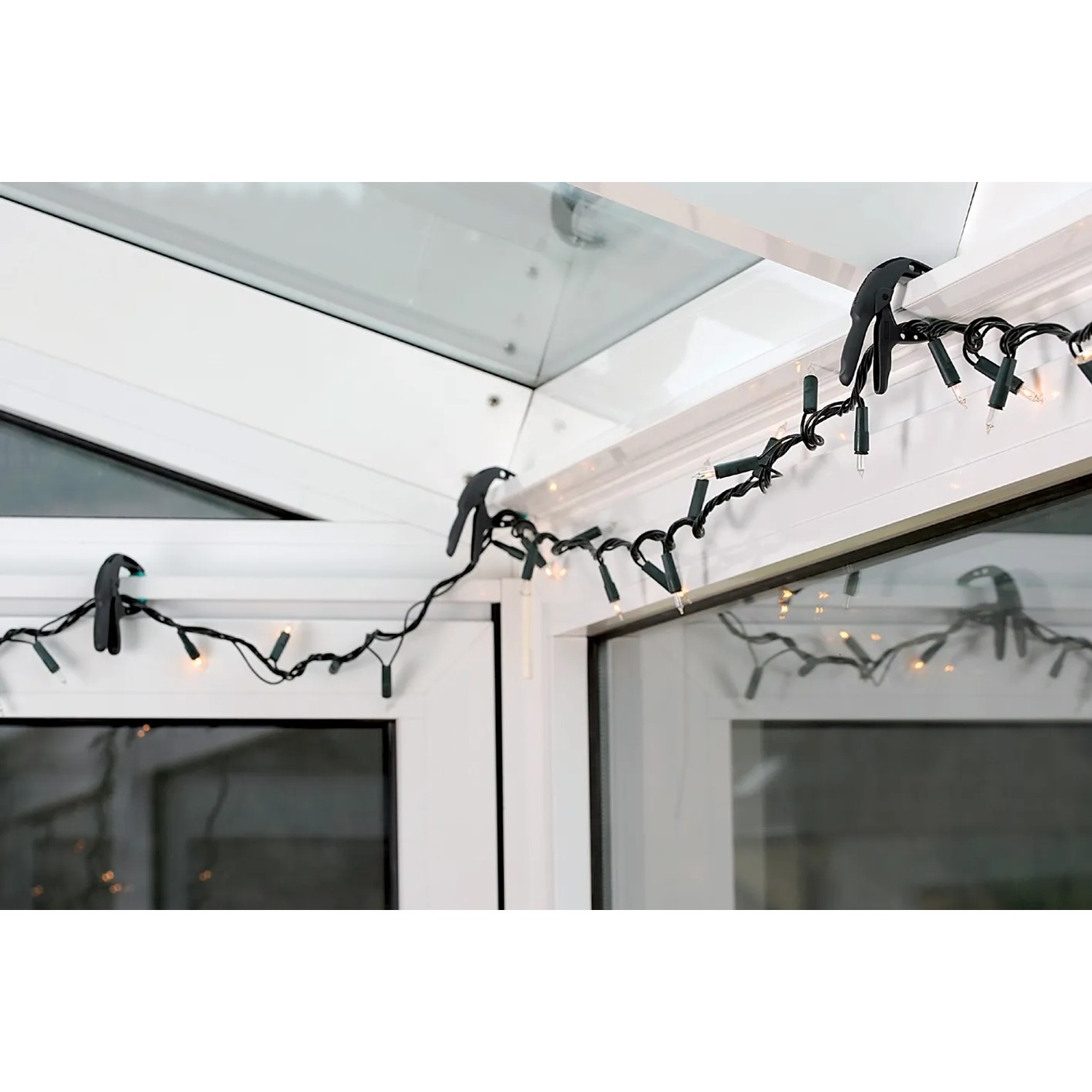Lichterkette befestigt mit wolfcraft Ergo-Federzwingen (3 cm) an einem Fensterrahmen.