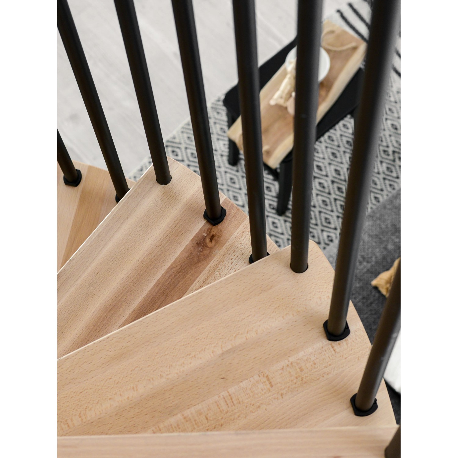 Detailaufnahme: Minka Spindeltreppe Spiral Wood Buche, schwarze Metallstäbe, helle Holzstufen.