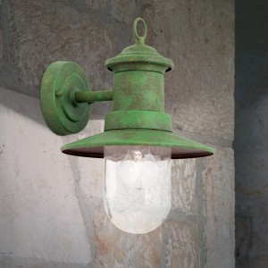 Rustikale Orion Außenwandleuchte, patiniert grün, aus Stahl mit klarem Glas, montiert an einer Steinwand. Vintage Design.