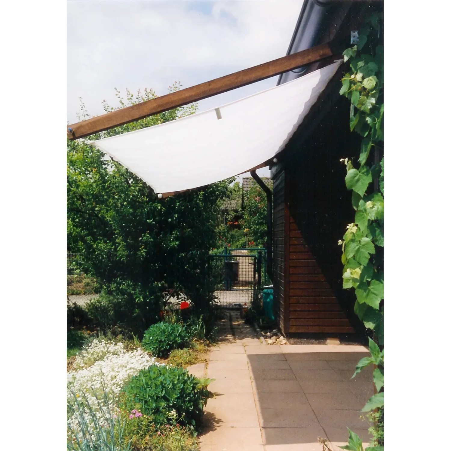 Viereckiges Floracord Sonnensegel in Elfenbein, 330x200 cm, montiert an einer Holzkonstruktion im Garten.