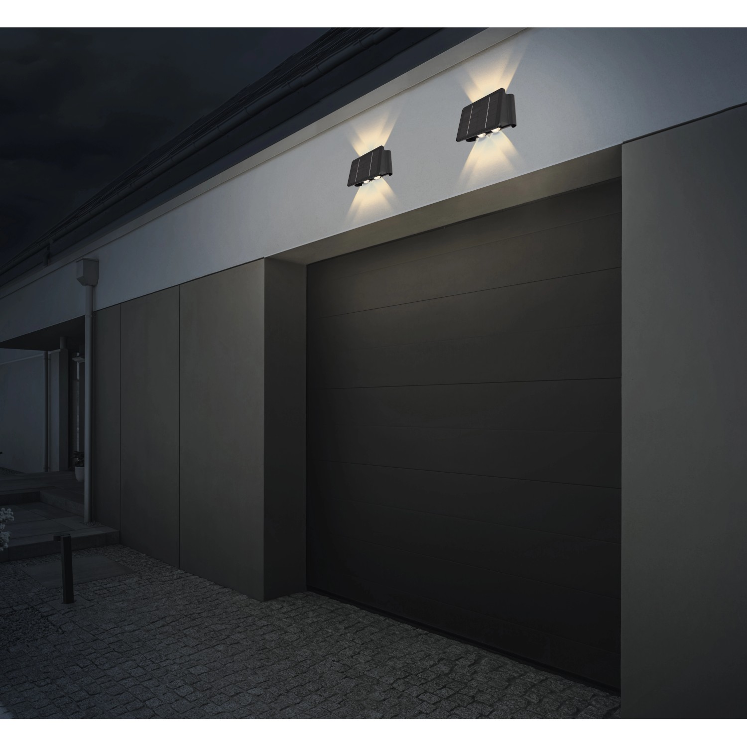 Zwei schwarze Globo LED Solar-Wandleuchten an einer Garagenwand.