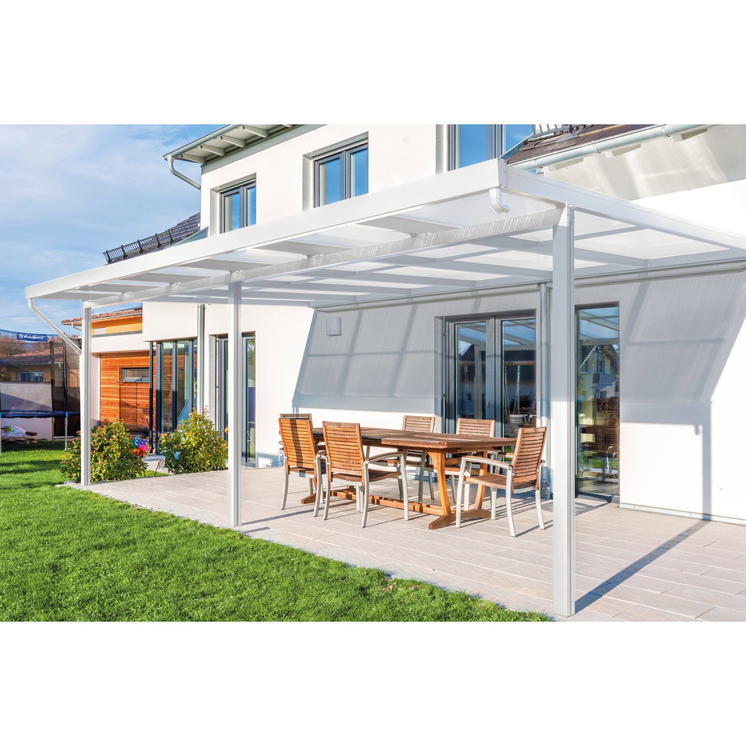 Weißes Gutta Terrassendach Premium mit Stegplatten aus Polycarbonat (5100x3060mm) über einer Terrasse mit Tisch und Stühlen.