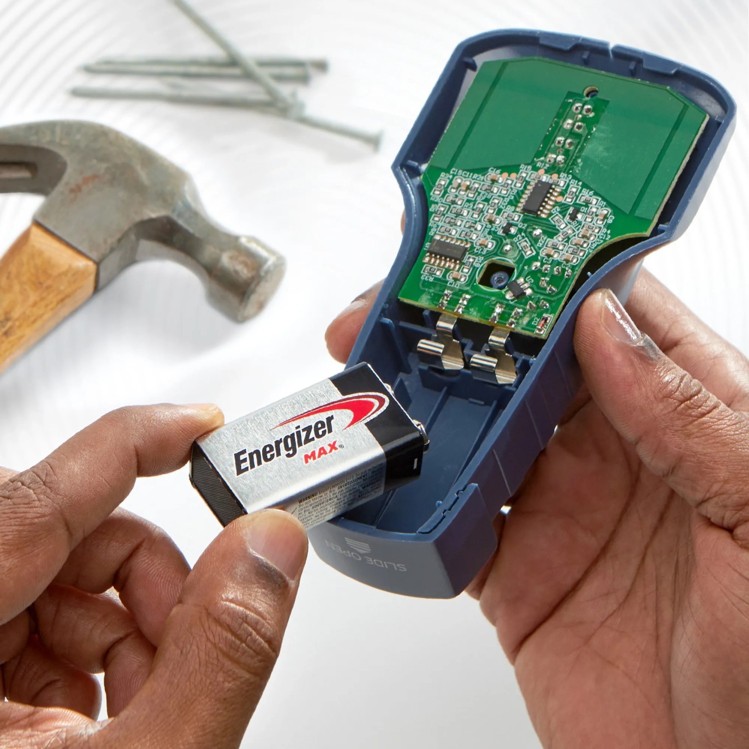Energizer 9V Batterie wird in ein elektronisches Gerät eingesetzt. Werkzeug im Hintergrund.