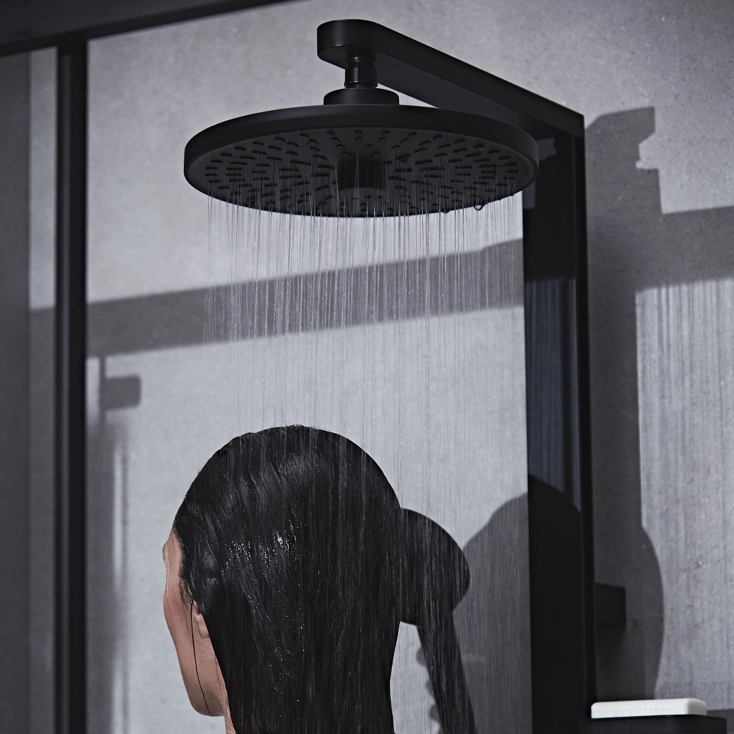 Ideal Standard Duschpaneel mit Regen- und Handbrause, Thermostat, Schwarz Matt. Frau duscht.