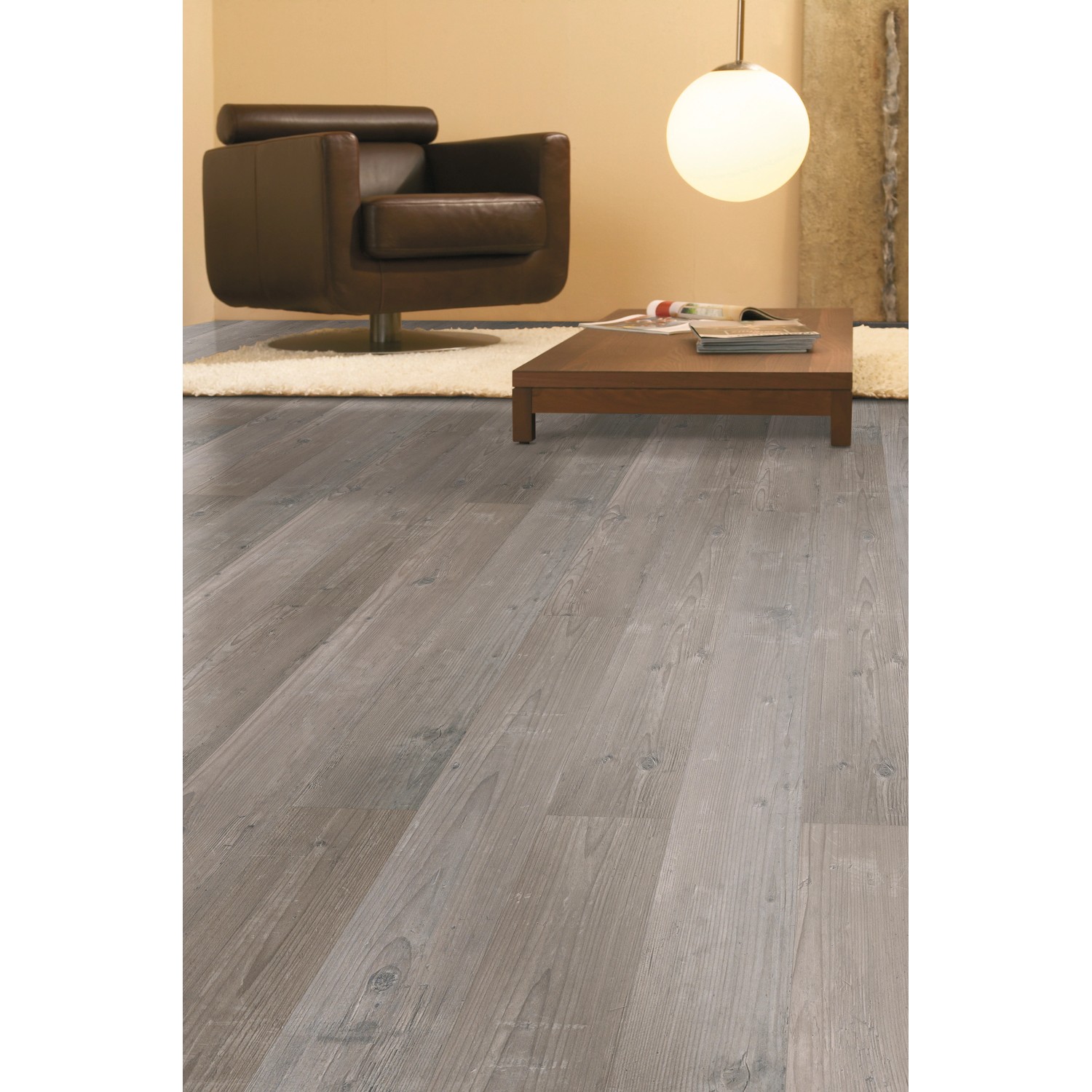 Verlegter Laminatboden Comfort Kiefer Vintage 7 mm im Wohnraum mit Sessel und Tisch.