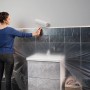 Frau streicht Wand mit Tesa Abdeckfolie Easy Cover Economy XL. Schutz vor Farbspritzern.