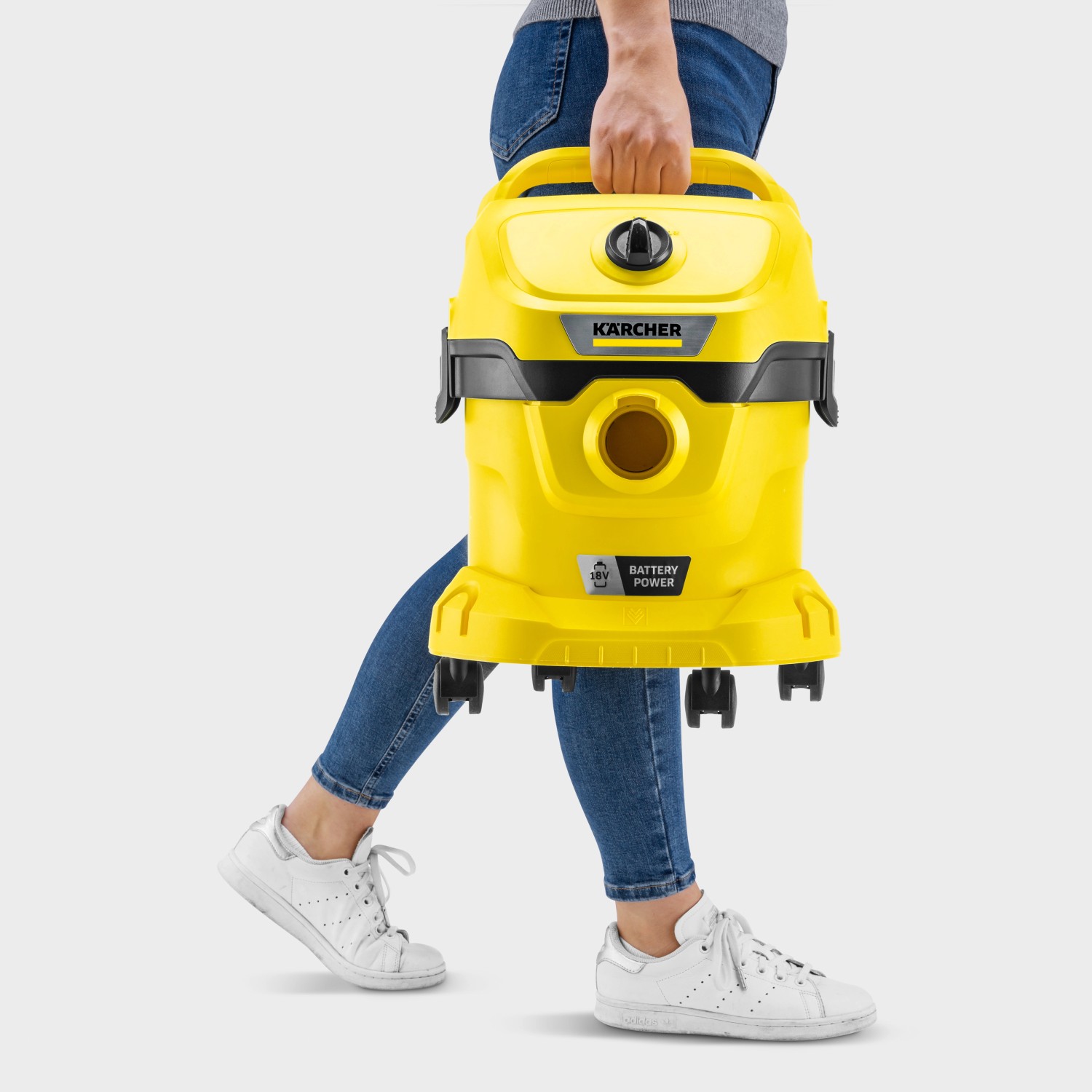Gelber Kärcher Akku Nass-Trockensauger WD 2-18, getragen von einer Person.