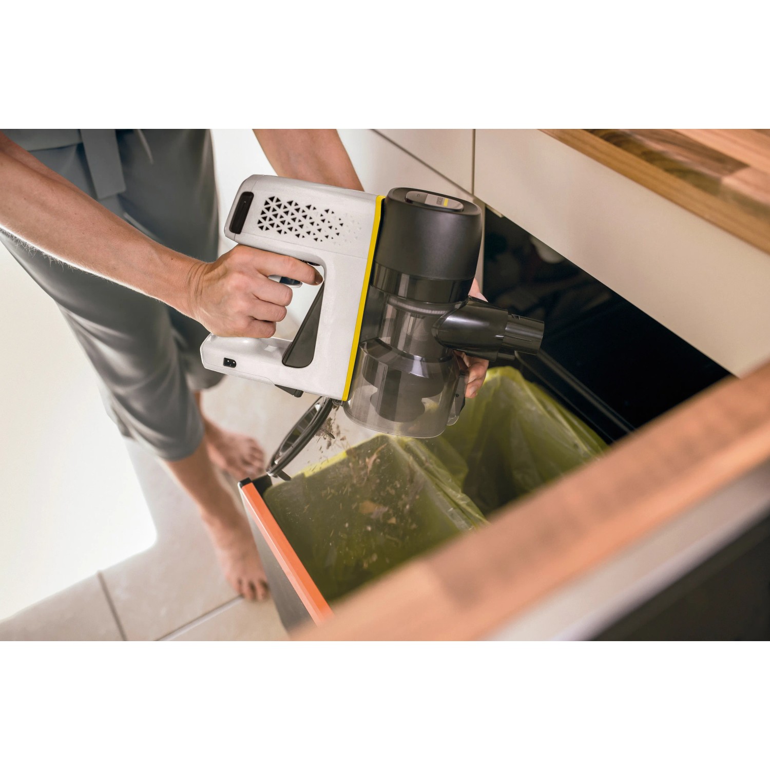 Kärcher Akku-Staubsauger VC 4 Cordless myHome beim Entleeren über einem Mülleimer.
