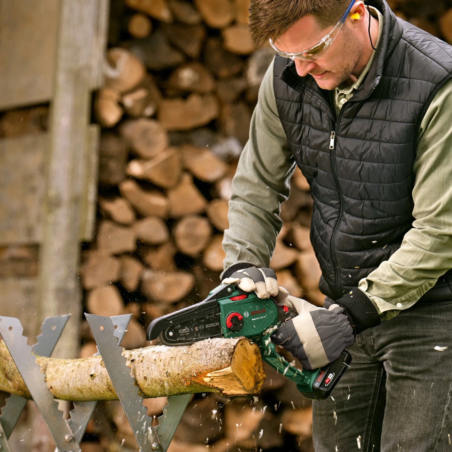 Mann sägt Holz mit dem Bosch Akku-Gehölzschneider EasyChain 18V-15-7.