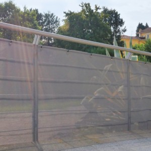 Graues Tenax Sichtschutznetz Texstyle Prive 1x5m am Zaun, mit Ösen zur Befestigung.