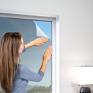 Frau bringt Is cool Gewebe Rolle (anthrazit, 140x150 cm) am Fenster an. Insektenschutz & Sonnenschutz.
