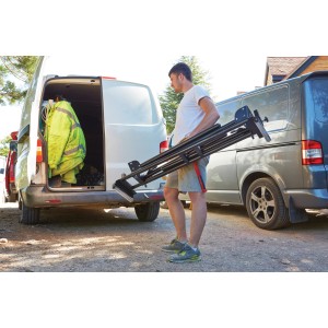 Mann trägt zusammengeklapptes Stanley FatMax Universal-Untergestell für Sägen zum Transporter.