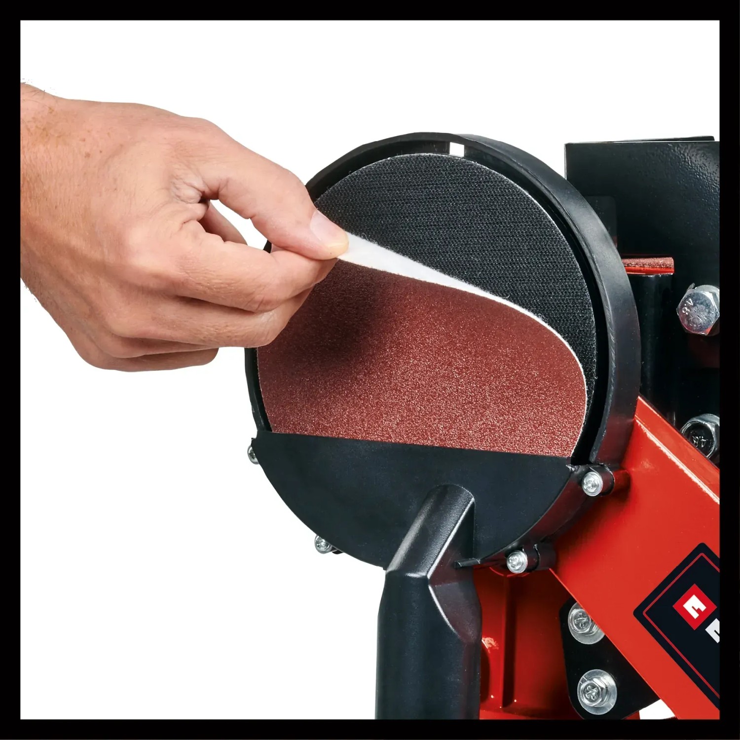 Einhell TC-US 380 Stand-Band-Tellerschleifer: Hand wechselt Schleifpapier auf dem Schleifteller.
