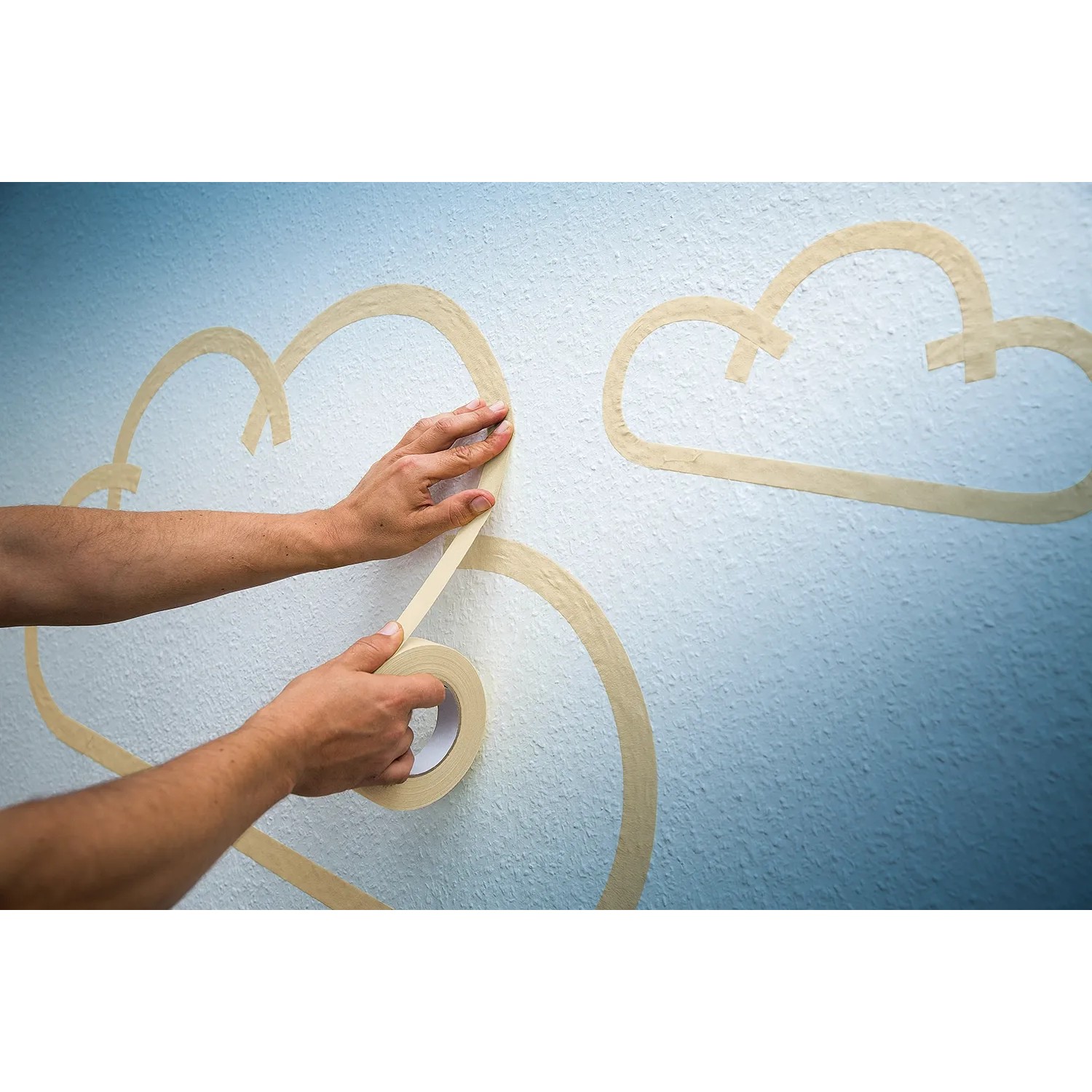 Anwendung von dehnbarem, beigem LUX Hochkrepp Klebeband zum Abkleben von Wolkenformen an einer Wand.