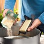 Person entleert Sägemehl aus Staubbox des Bosch Exzenterschleifers PEX 220 A, hält Microfilter.
