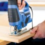 Blaue LUX Stichsäge E-STS-23 schneidet Holzbrett. Handwerkzeug für präzise Schnitte.