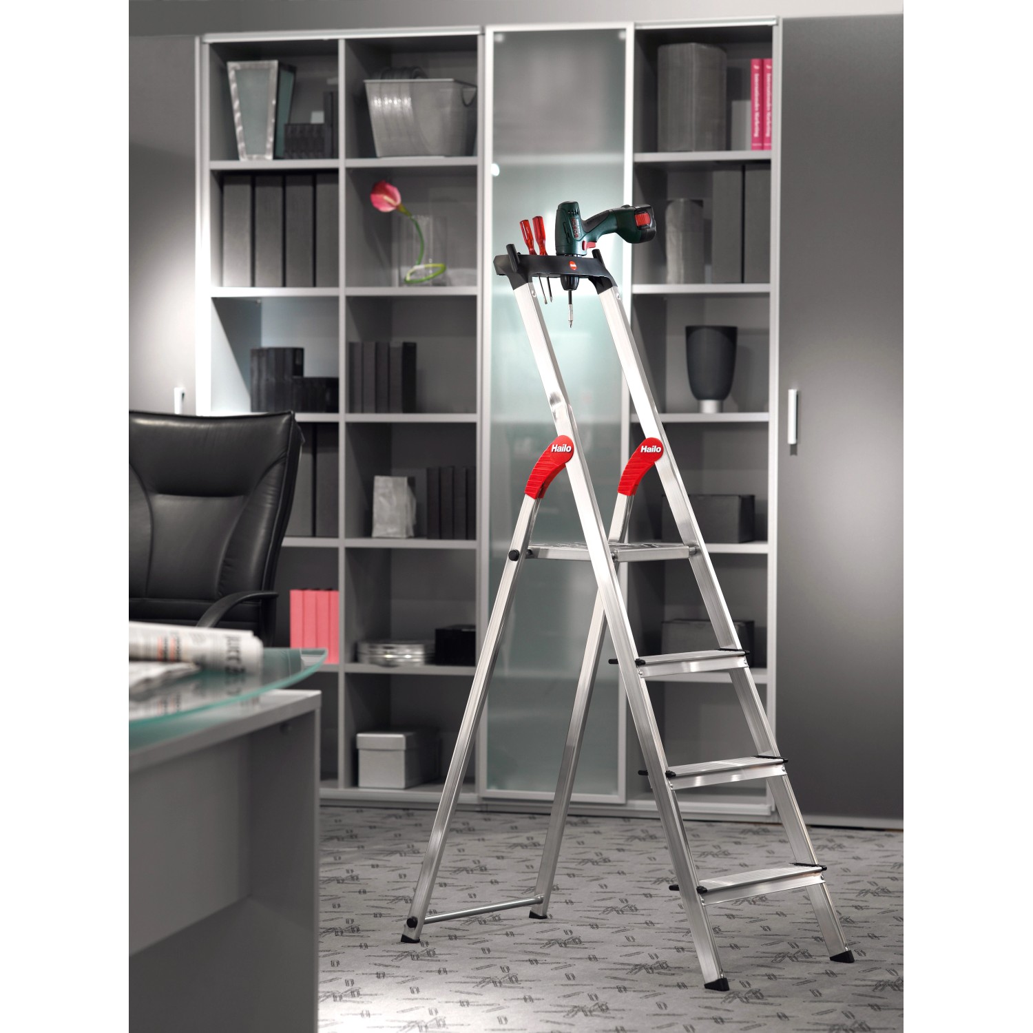 Hailo Alu-Haushaltsleiter XXL Comfortline mit 5 Stufen und Ablageschale vor Regal.