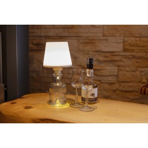 REV Ritter LED Flaschenleuchte Lamprusco, Akku, weiß-silber, auf Tisch mit Flasche und Gläsern. Dekoleuchte für Innen und Außen.