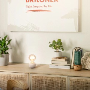 Brilo Amba Tischleuchte aus beiger Keramik mit E27 Filament-Leuchtmittel auf Sideboard. Dekorative Wohnraumlampe.