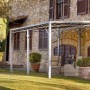 Feuerverzinkte Eleo Pergola Metall Sicilia (252,2x408x304 cm) vor Hauswand mit Gartenmöbeln.