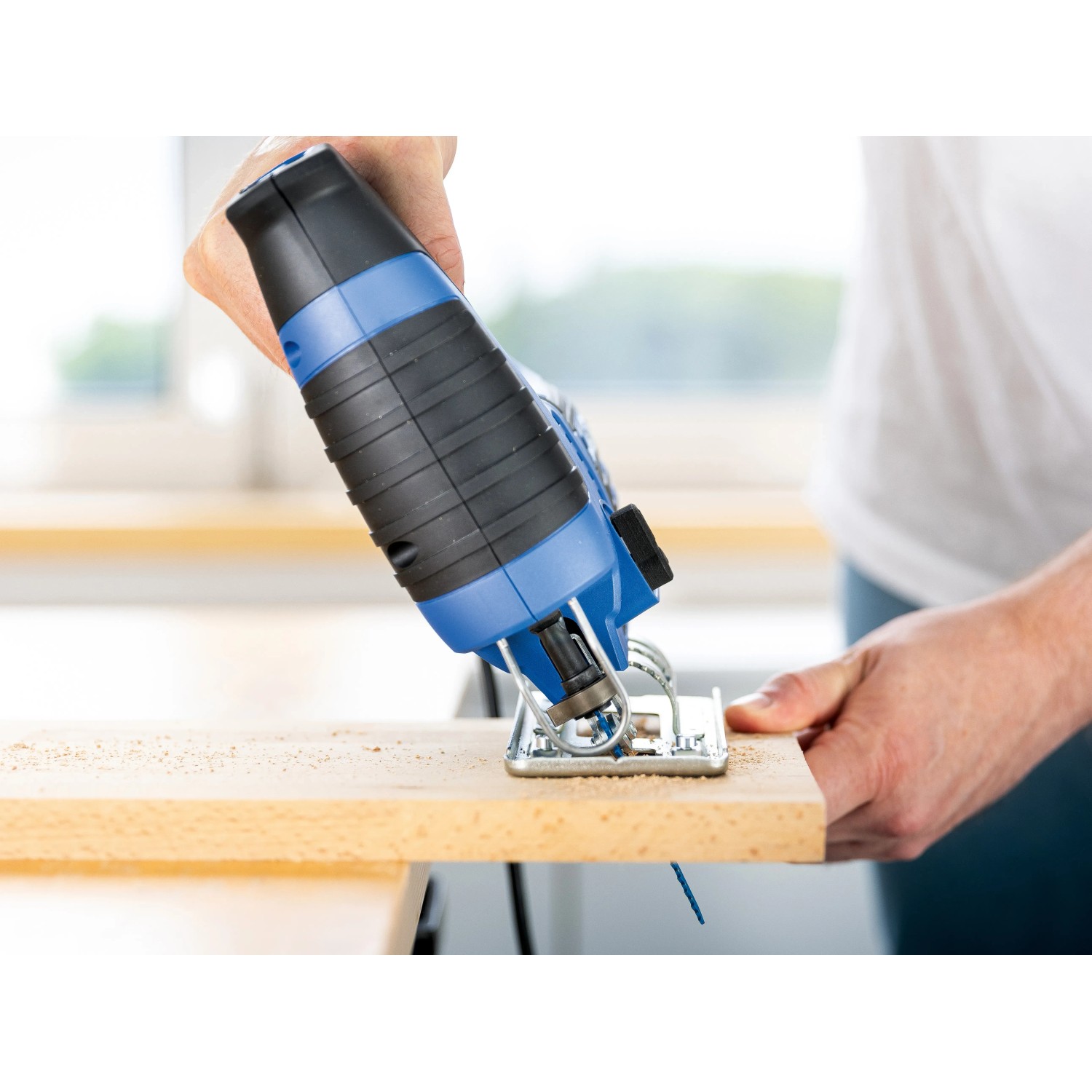 LUX Stichsäge E-STS-23 beim Sägen von Holz. Blaue Stichsäge mit Hand.