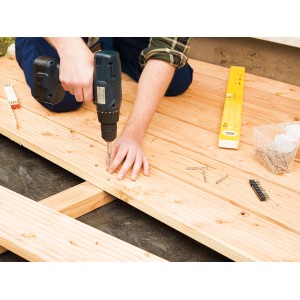 Terrassenbau: Mann schraubt Linsensenkkopf Terrassenschraube mit TX-Antrieb in Holzdiele.