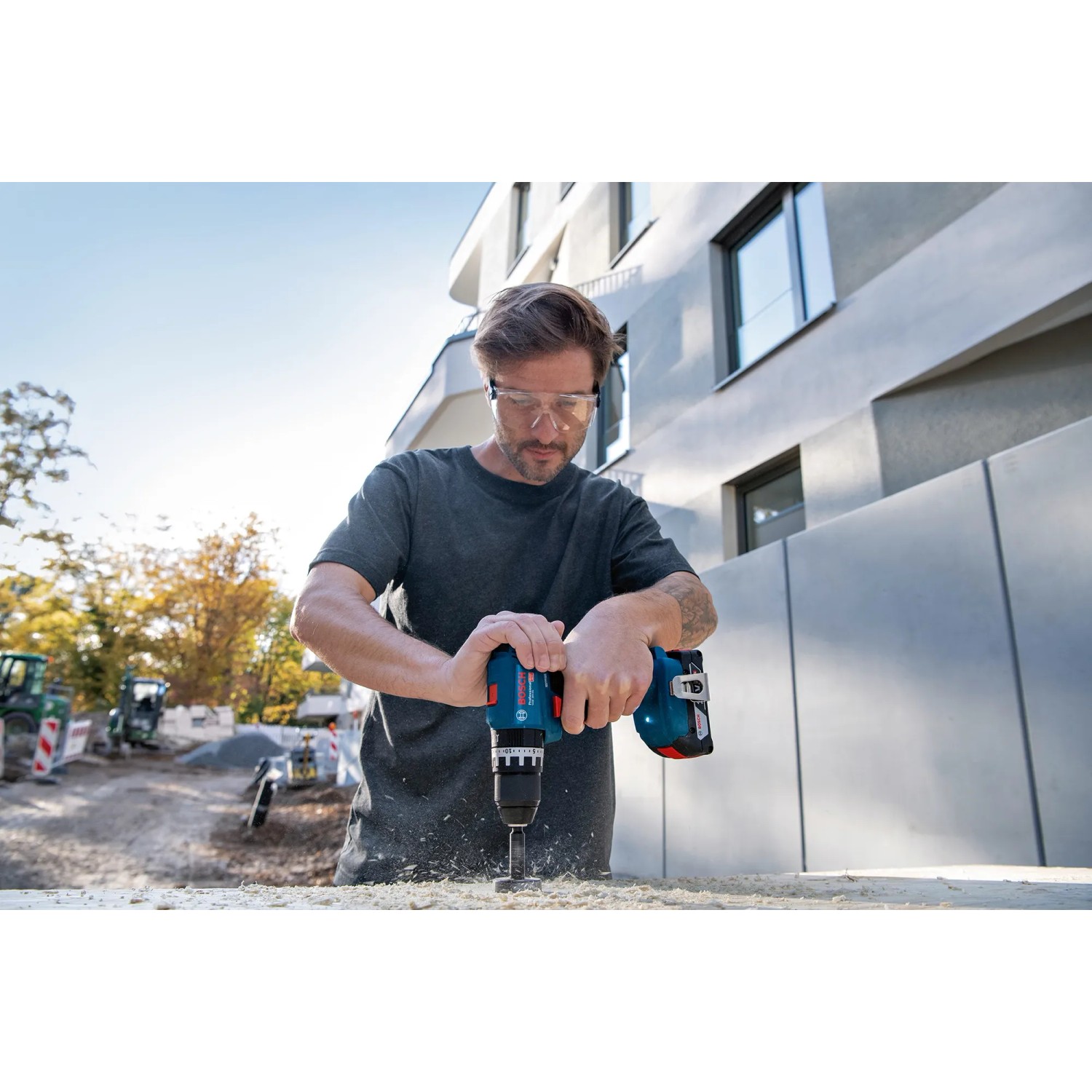 Mann bohrt mit Bosch Professional Akku-Schlagbohrschrauber. Werkzeug-Set mit 18V-Werkzeugen.