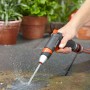 Gardena Premium Reinigungsspritze in Aktion: Wasserstrahl reinigt Steinboden im Garten.