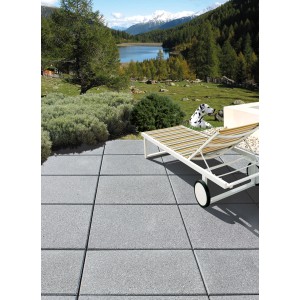 Häusler Landhaus Steinplatte steingrau, 50x50 cm, auf Terrasse mit Liege und Blick in die Natur.