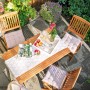 Gartenszene mit Greenville Klappstühlen aus Holz ohne Armlehnen und Tisch mit Dekoration.