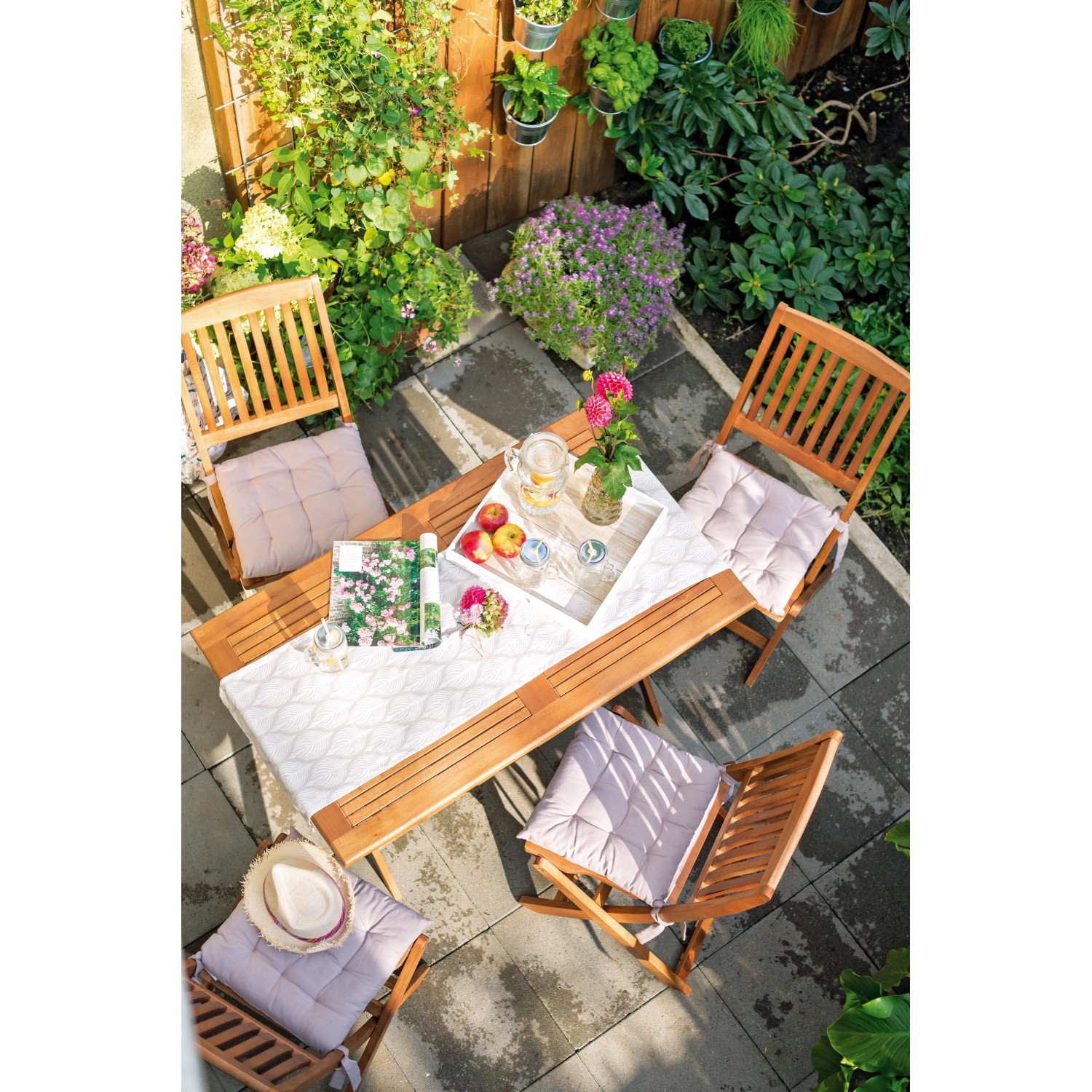 Gartenszene mit Greenville Klappstühlen aus Holz ohne Armlehnen und Tisch mit Dekoration.