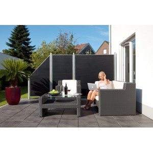 Anthrazitfarbener Gartenzaun Weave Lüx als Sichtschutz im Garten mit Frau auf der Couch.