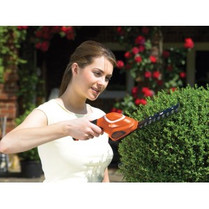 Frau schneidet Buchsbaum mit Black+Decker Akku-Gras- und Strauchschere GLS700.