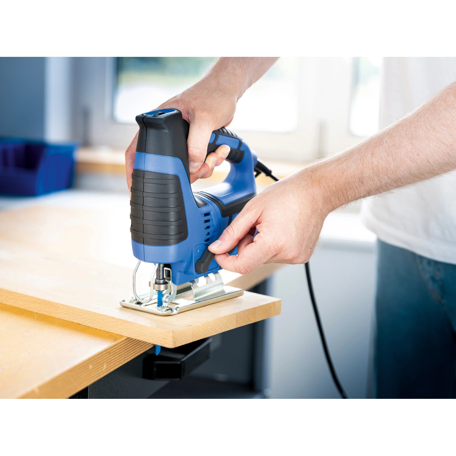 LUX Stichsäge E-STS-23 beim Sägen von Holz. Blaue Stichsäge mit schwarzem Griff.