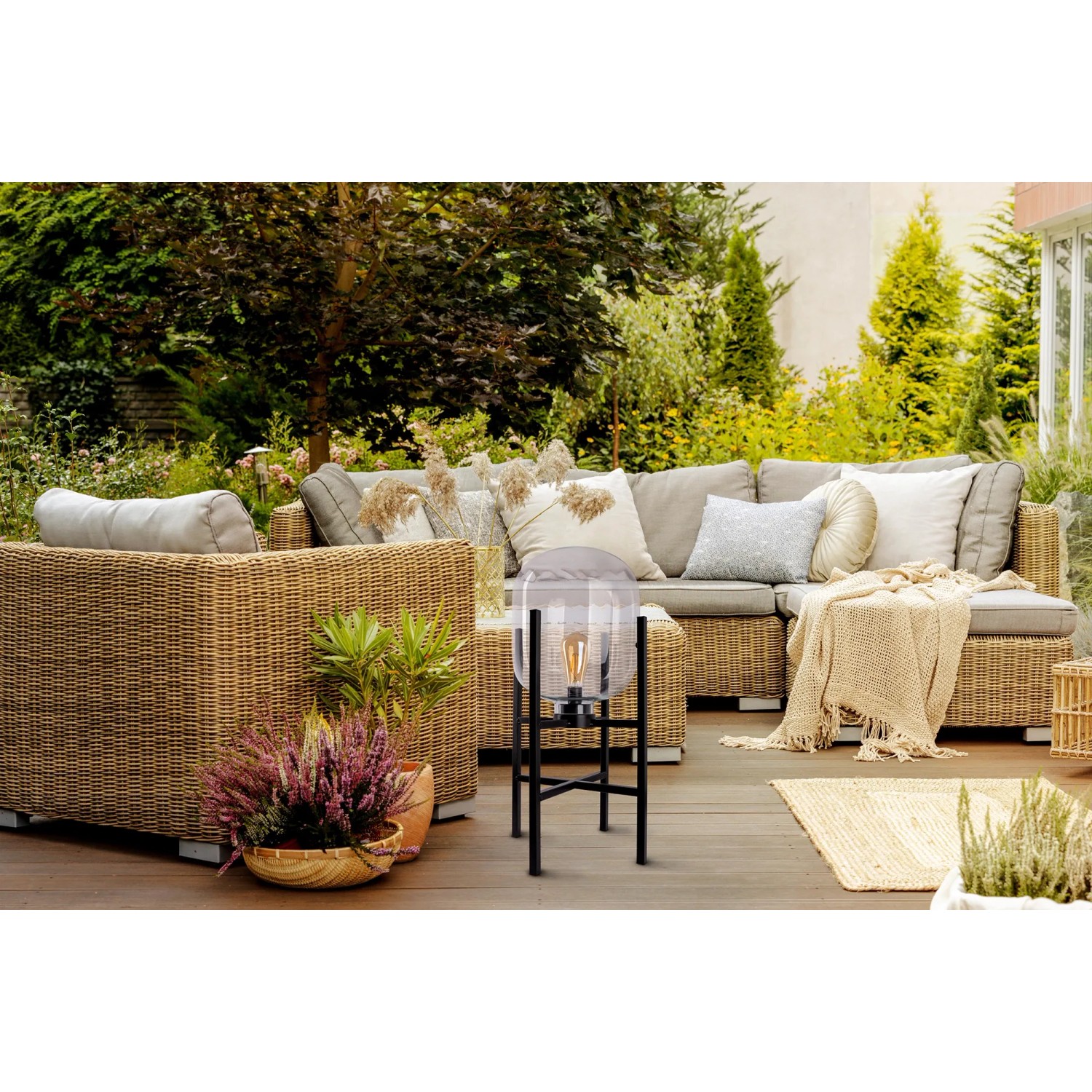 Schwarze LED-Akku-Sockelleuchte Lora (Ø 26 cm) auf Terrasse mit Rattansitzgruppe.
