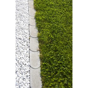 Graue Mähkante aus Beton zwischen Rasen und weißen Ziersteinen zur Gartengestaltung.