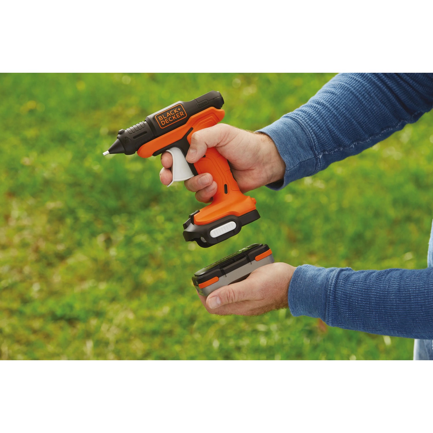Black+Decker Akku-Heißklebepistole BDCGG12N 12 V mit Akku in Hand vor grünem Hintergrund.